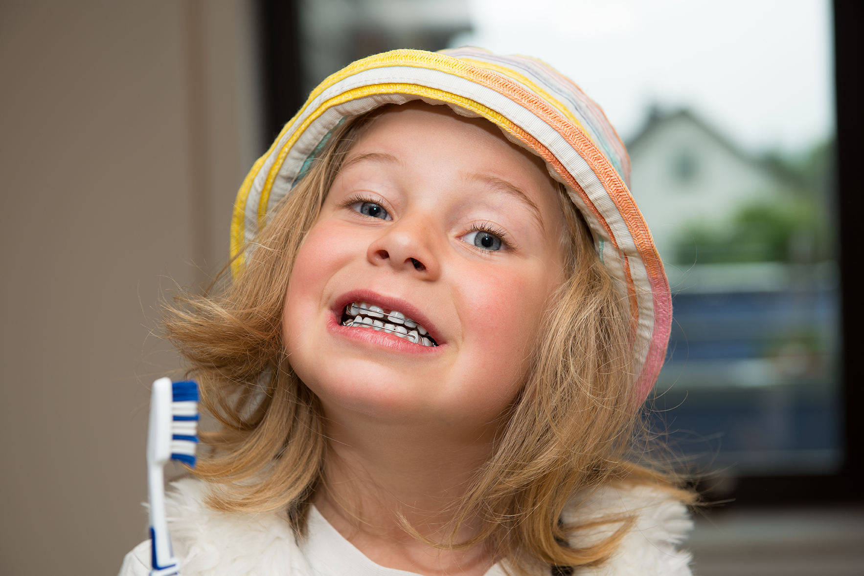 little girl with braces retainer and toothbrush