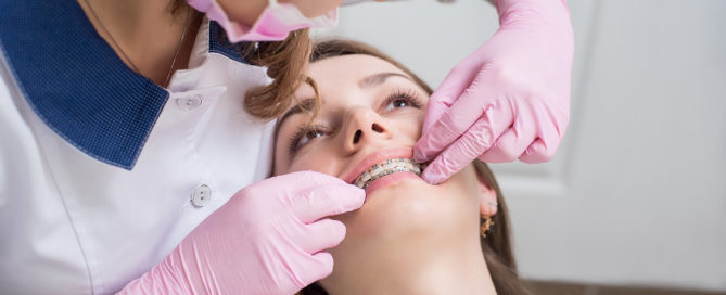 orthodontist checking female's braces