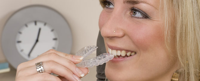 smiling woman inserts invisalign